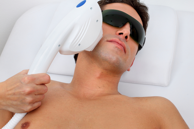doctor treats the face of a man with a modern laser epilator.